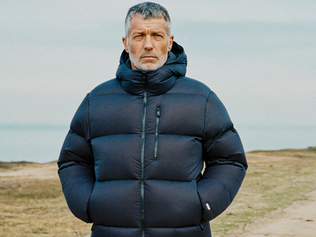 Man in a navy hooded insulated puffer jacket on a winter coastal path